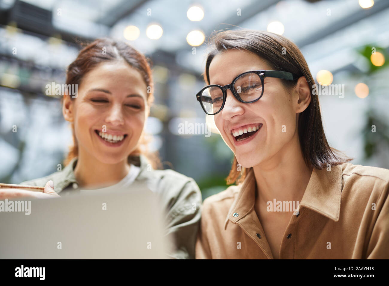 Porträt von zwei zeitgenössische junge Frauen an Laptop Bildschirm schaut und lächelnd, während sie das Mittagessen im Cafe, kopieren Raum Stockfoto
