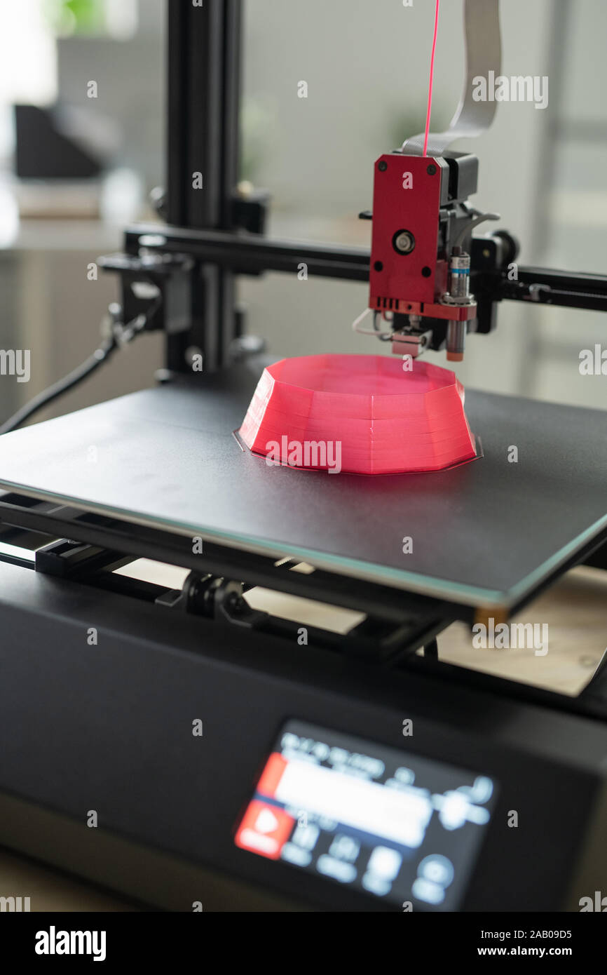 Druckkopf von 3d Drucker über einen Teil von Pink rundes Objekt auf der Arbeitsoberfläche während des Druckens Stockfoto