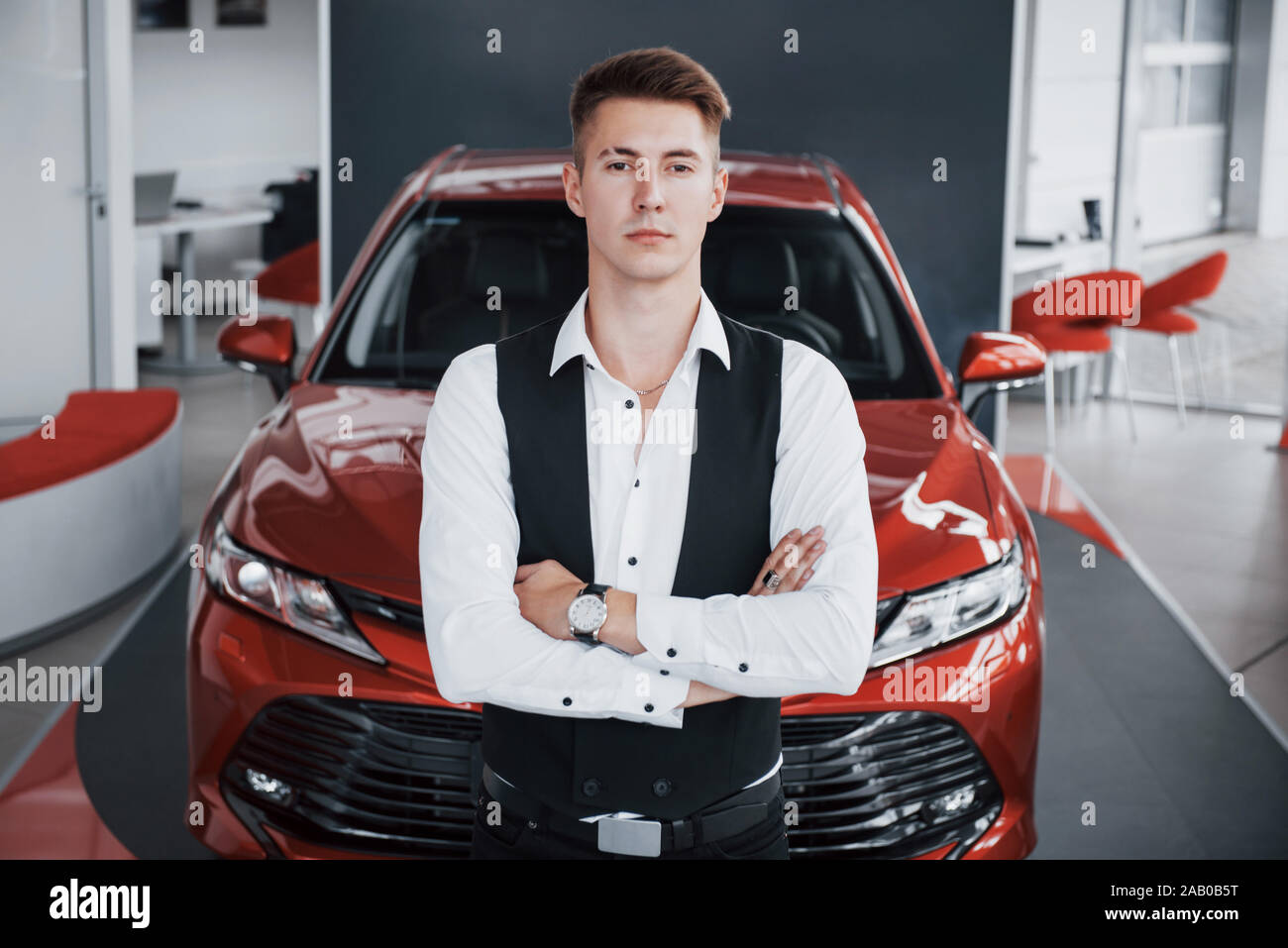 Ein junger gut aussehender Geschäftsmann steht mit dem Auto Stockfoto