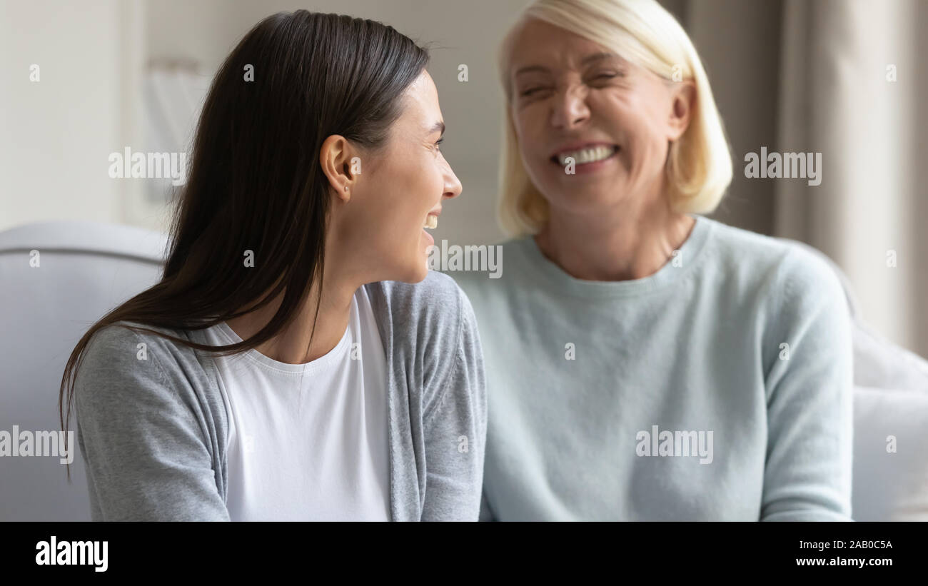 Fröhlichen erwachsenen Tochter in angenehmen lustige Gespräch mit älteren Mutter Stockfoto