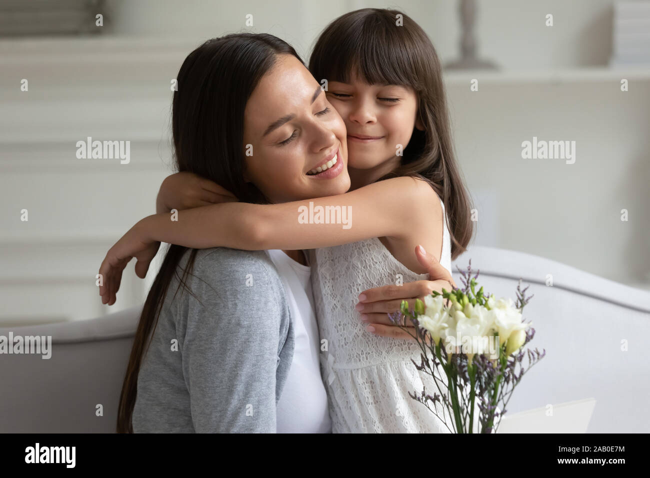 Liebevolle Mutter kuscheln Tochter dankt ihr für Blumen Geburtstag Stockfoto