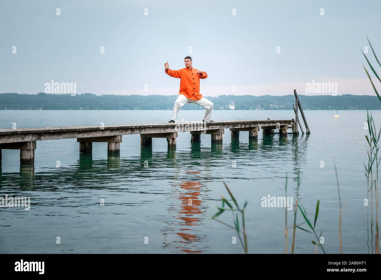 Ein Mann, der am fruehen Morgen Qi-Gong-Uebungen am Starnberger See durchfuehrt Stockfoto