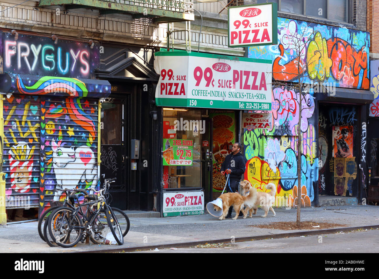 Eine Person mit Hunden geht hinunter eine bunte Urban Street im Stadtteil East Village in Manhattan, New York, NY Stockfoto