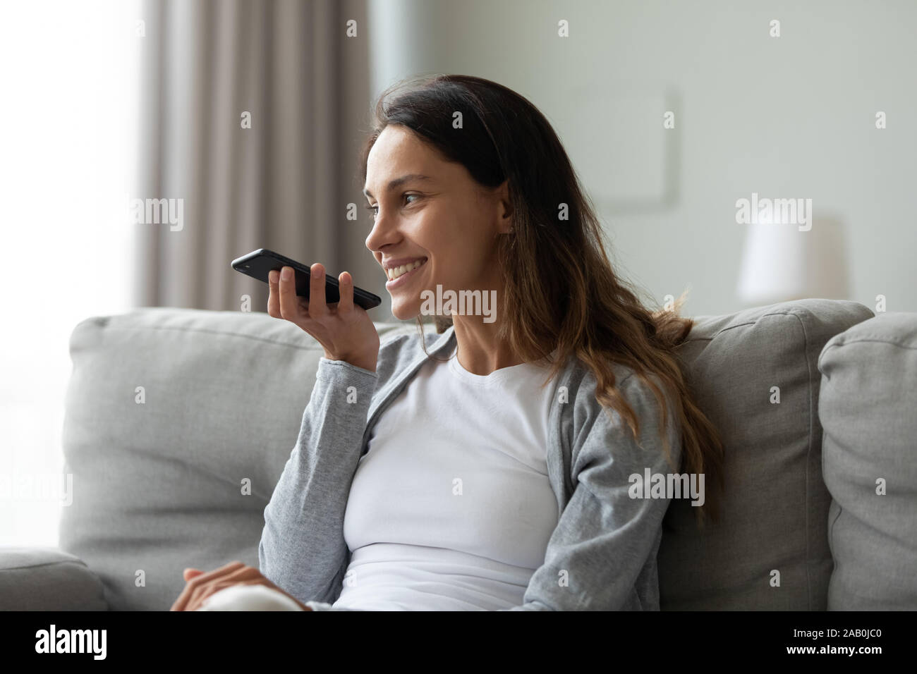 Frau verbrachte Zeit zu Hause halten Sie das Smartphone mit der Voice Messaging Stockfoto