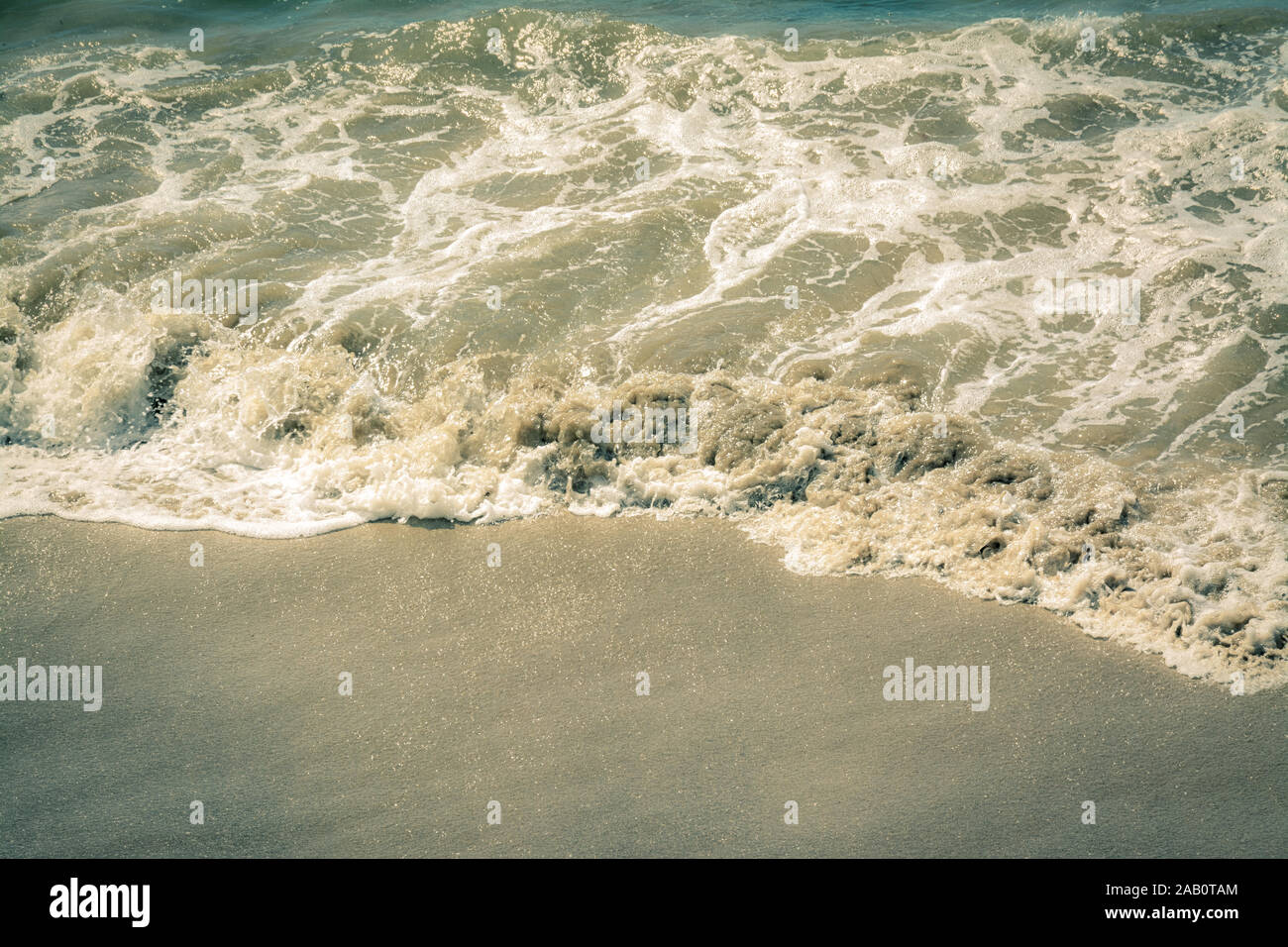 In der Nähe der braunen Wasser, kleine Wellen am Strand mit grobem Sand Textur Stockfoto