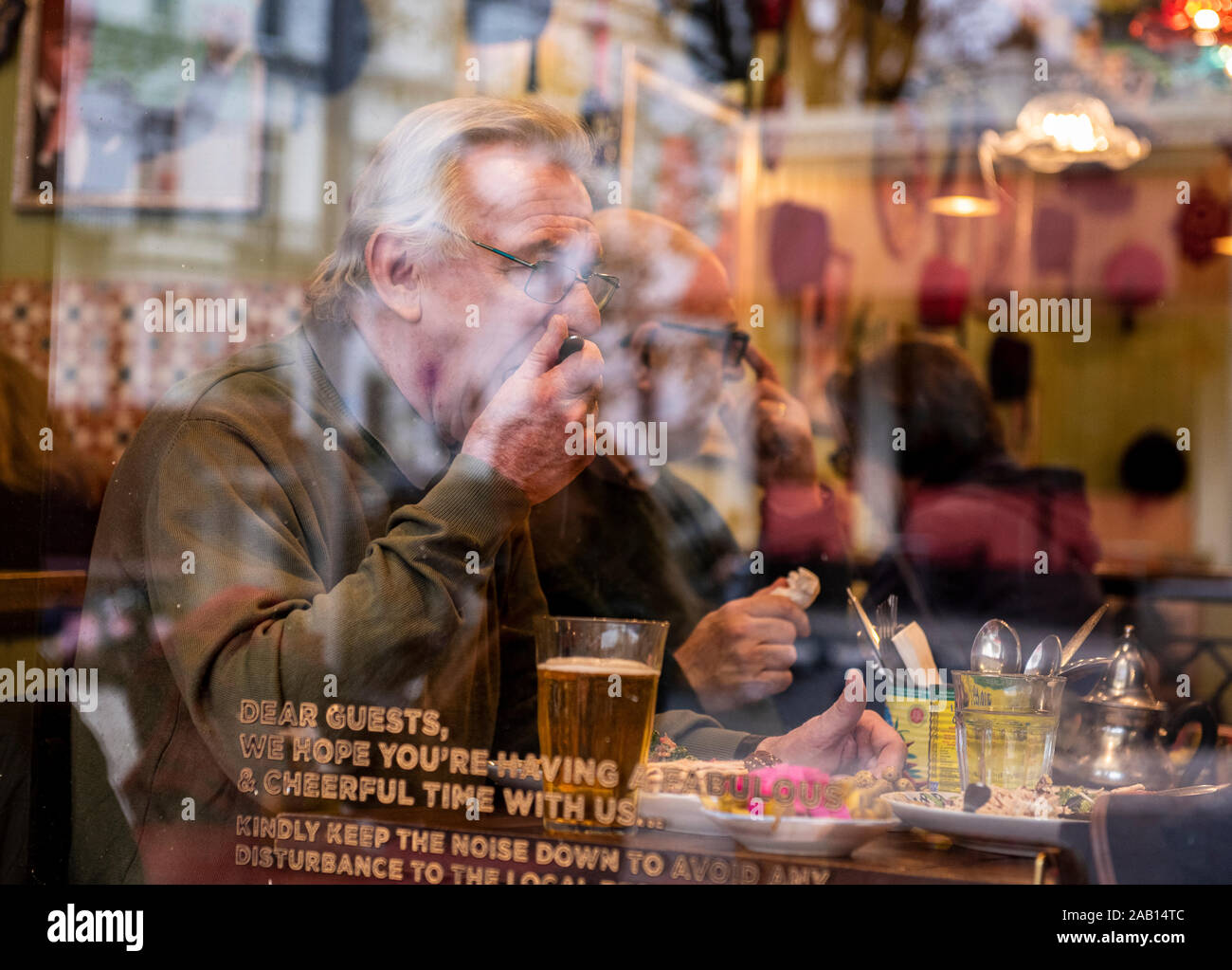 Älterer Mann mit dem grauen Haar Brille trägt das Mittagessen durch die Fenster in das Cafe. South Kensington, London, England, UK. Stockfoto