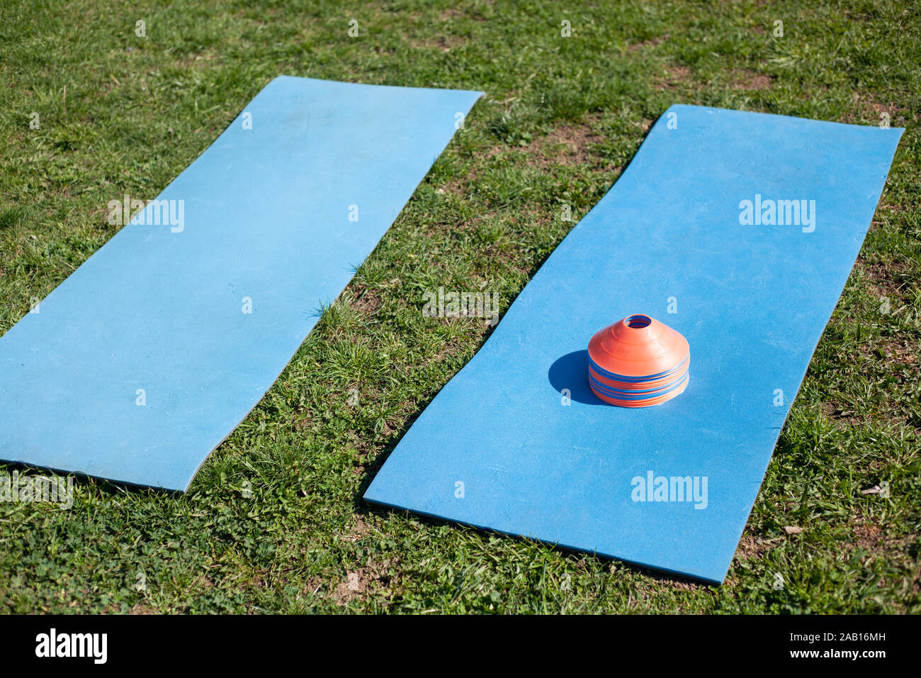 Blau Yoga Matten liegen auf dem Rasen. Matte für die Ausbildung. Vorbereitung für sportliche Übungen an der frischen Luft. Ausrüstung für die Übung. Elemente im Stadion. Stockfoto
