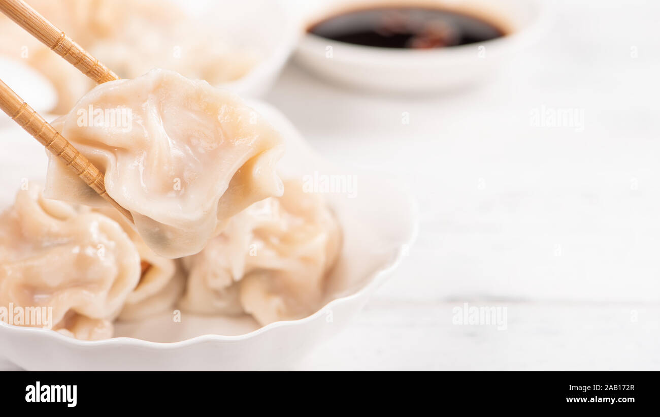 Frische, Köstliche gekochte Schweinefleisch, Garnelen Gyoza-teigtaschen auf weißem Hintergrund mit Sojasauce und Stäbchen, Nahaufnahme, Lifestyle. Hausgemachte Design Konzept. Stockfoto