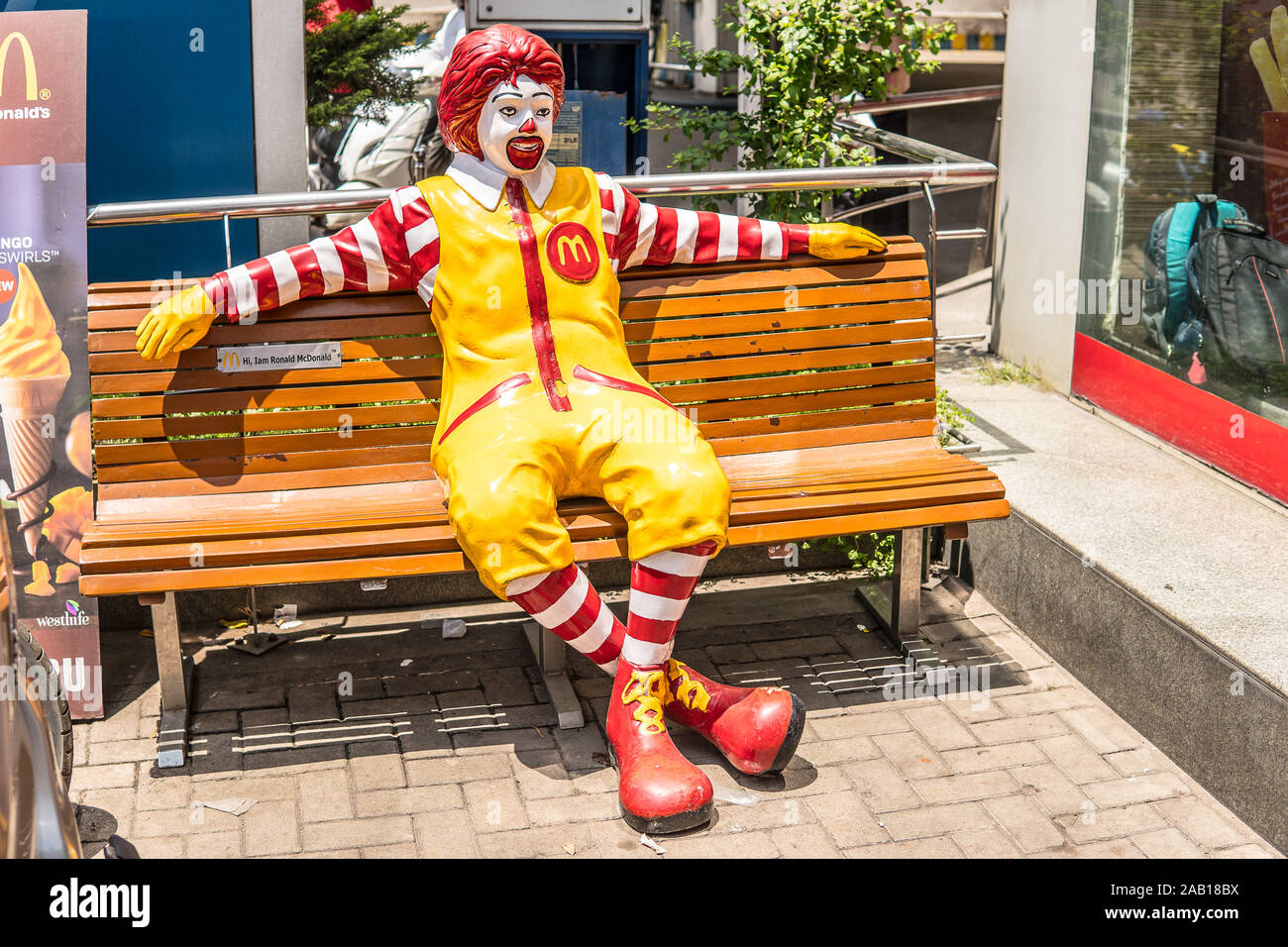 Indien, Bengaluru City, Ronald McDonald Sitzbank, Grüße an alle Kunden, Maskottchen für Kinder, gelb M Symbol von McDonald Restaurant Stockfoto