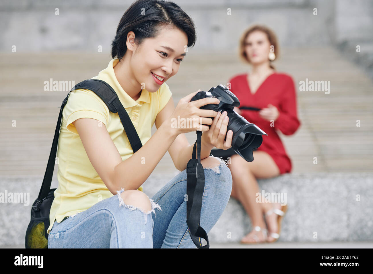 Gerne Fotografin Kontrolle der Fotos auf dem Bildschirm der Digitalkamera nach Schießen Modell im Freien Stockfoto