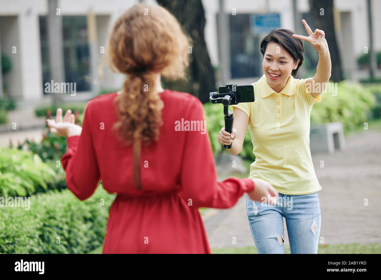 Aufgeregt asiatische Frau mit Smartphone mit zwei Fingern an Blogger, die darauf hinweist, dass Sie schießen starten Stockfoto