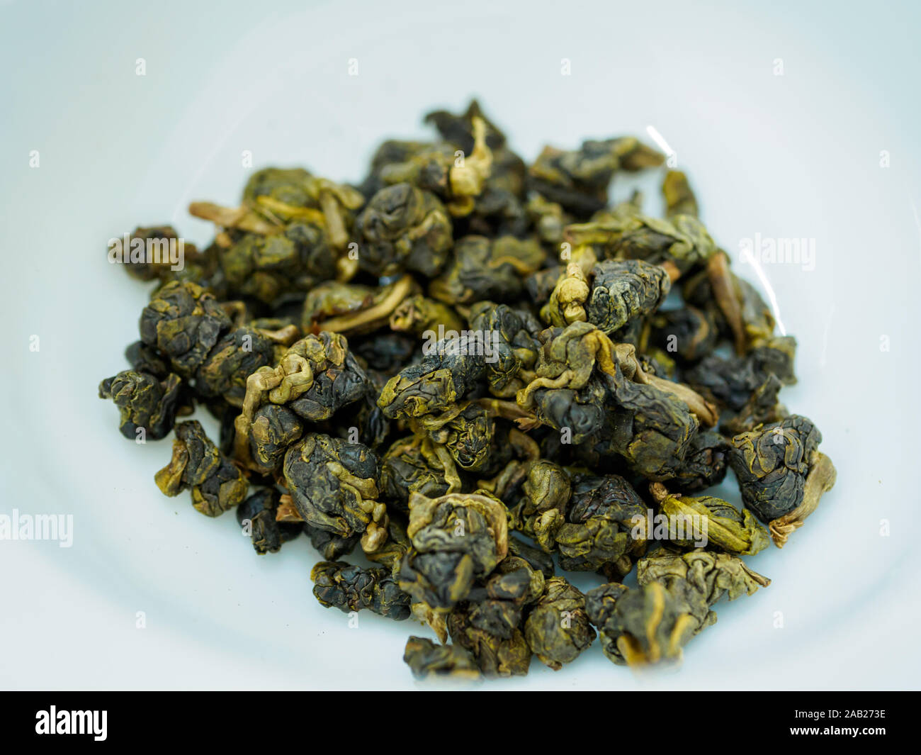 Nahaufnahme Makroaufnahme der trockenen China Green oolong Tee Kugeln in einem weißen Porzellan Schale Stockfoto