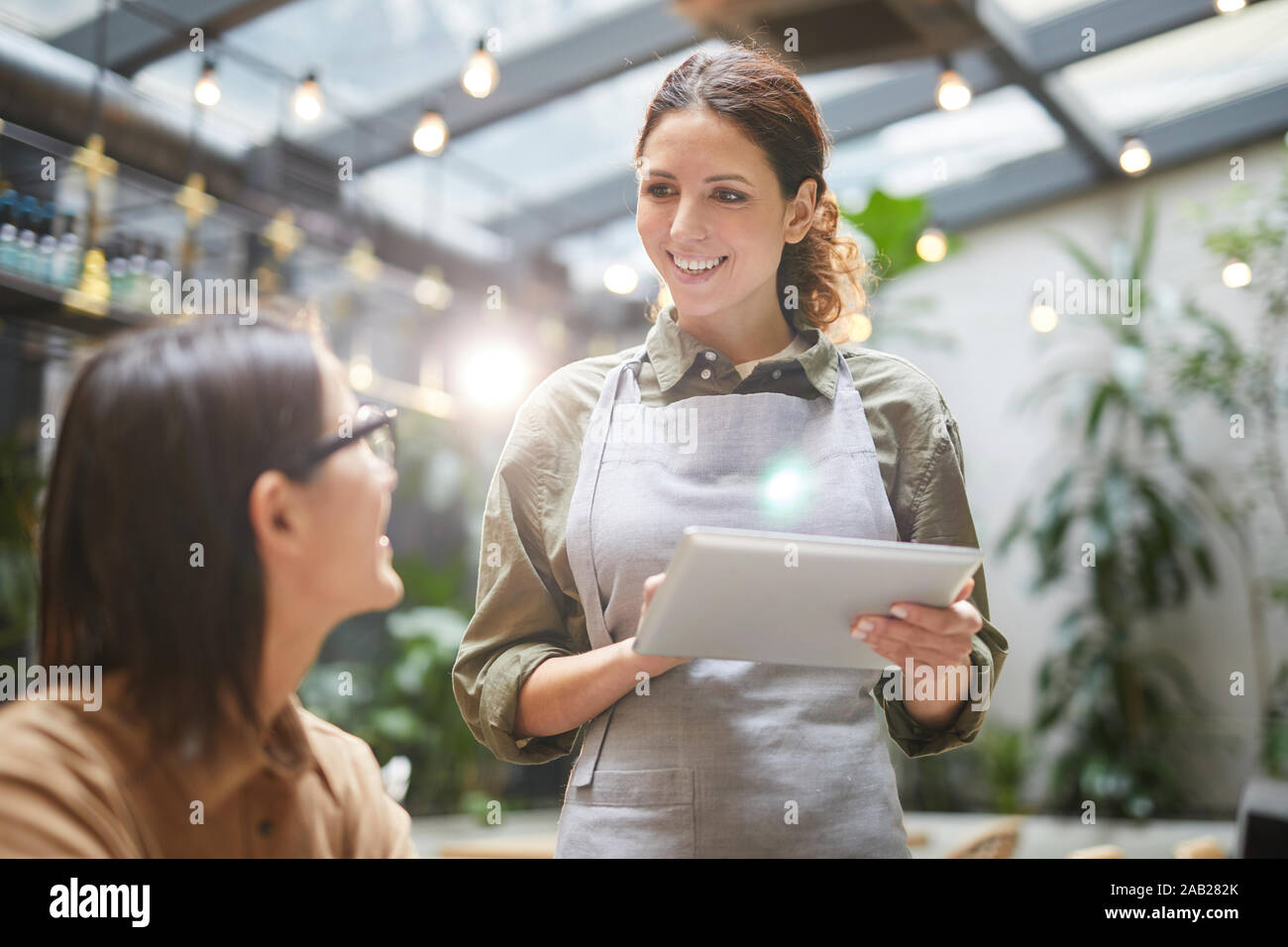 Taille bis Porträt der jungen Kellnerin Holding digital Tablet während der Bestellung des Kunden bei Outdoor Cafe Terrasse, Kopie Raum Stockfoto