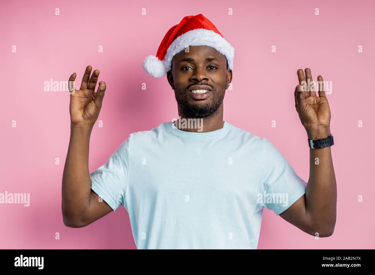 Alles in Ordnung. Sorglos glücklich dunkelhäutigen Mann in Santa Hut mit ok Zeichen mit beiden Händen, demonstriert seine Vereinbarung, gegen Rosa posing Stockfoto