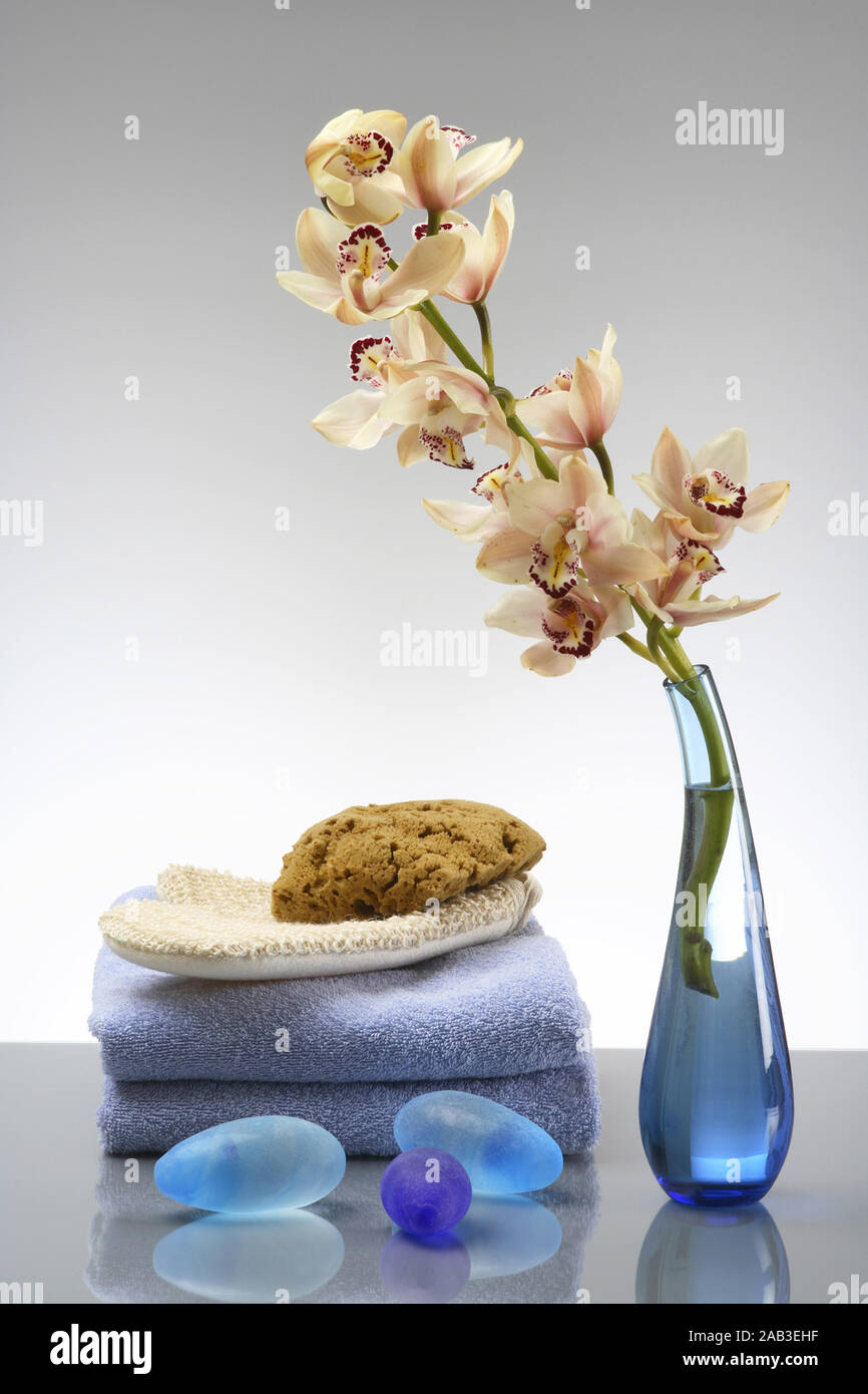Orchidee mit Handtuecher, Schwamm, Massagehandschuh und blaue Steine Stockfoto