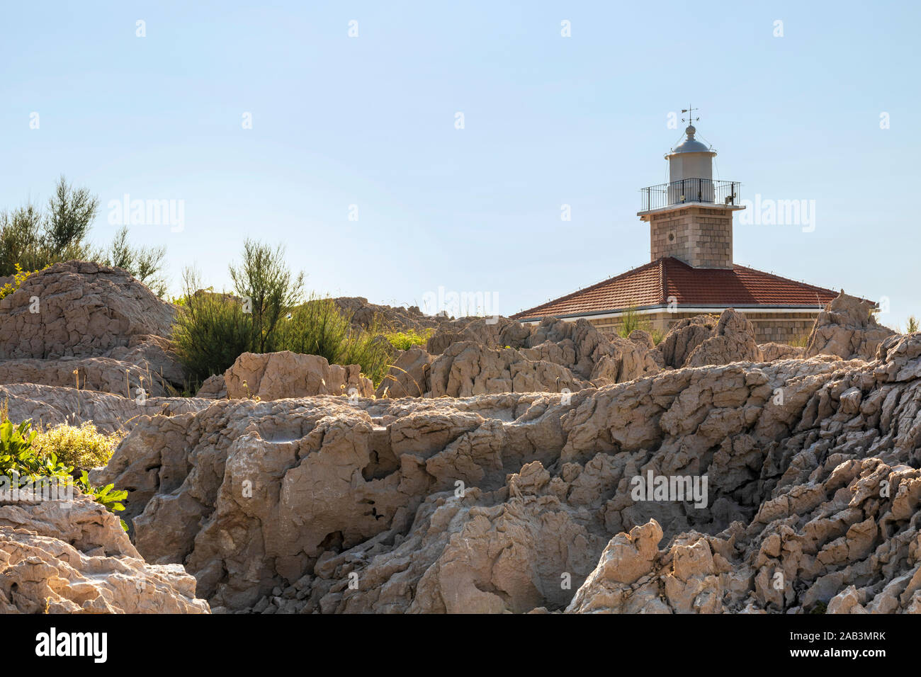 Von Makarska in Dalmatien, Kroatien. Blick von der Halbinsel an einem sonnigen Tag im Sommer. Raue Natur mit viel Grün, Felsen und die st. Peter Leuchtturm. Holid Stockfoto