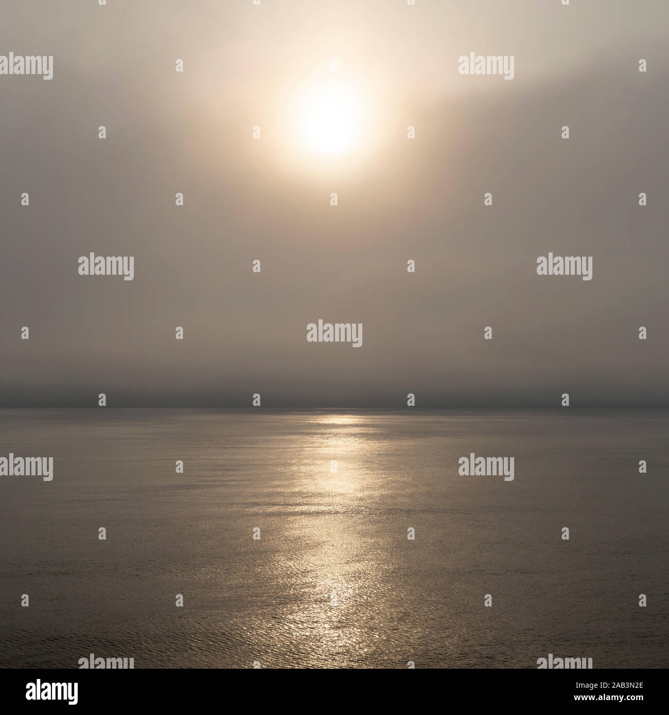 Morgen Sonnenschein glänzt durch Nebel an der Nordsee. Das Meer ist ruhig und die Sonne spiegelt Golden auf seiner Oberfläche. Stockfoto