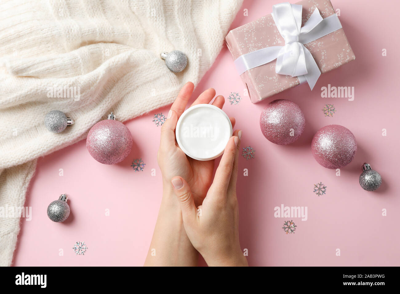 Frau mit Krug winter Creme für die Haut, Weihnachten Spielzeug, Pullover, Handschuhe auf rosa Hintergrund Stockfoto