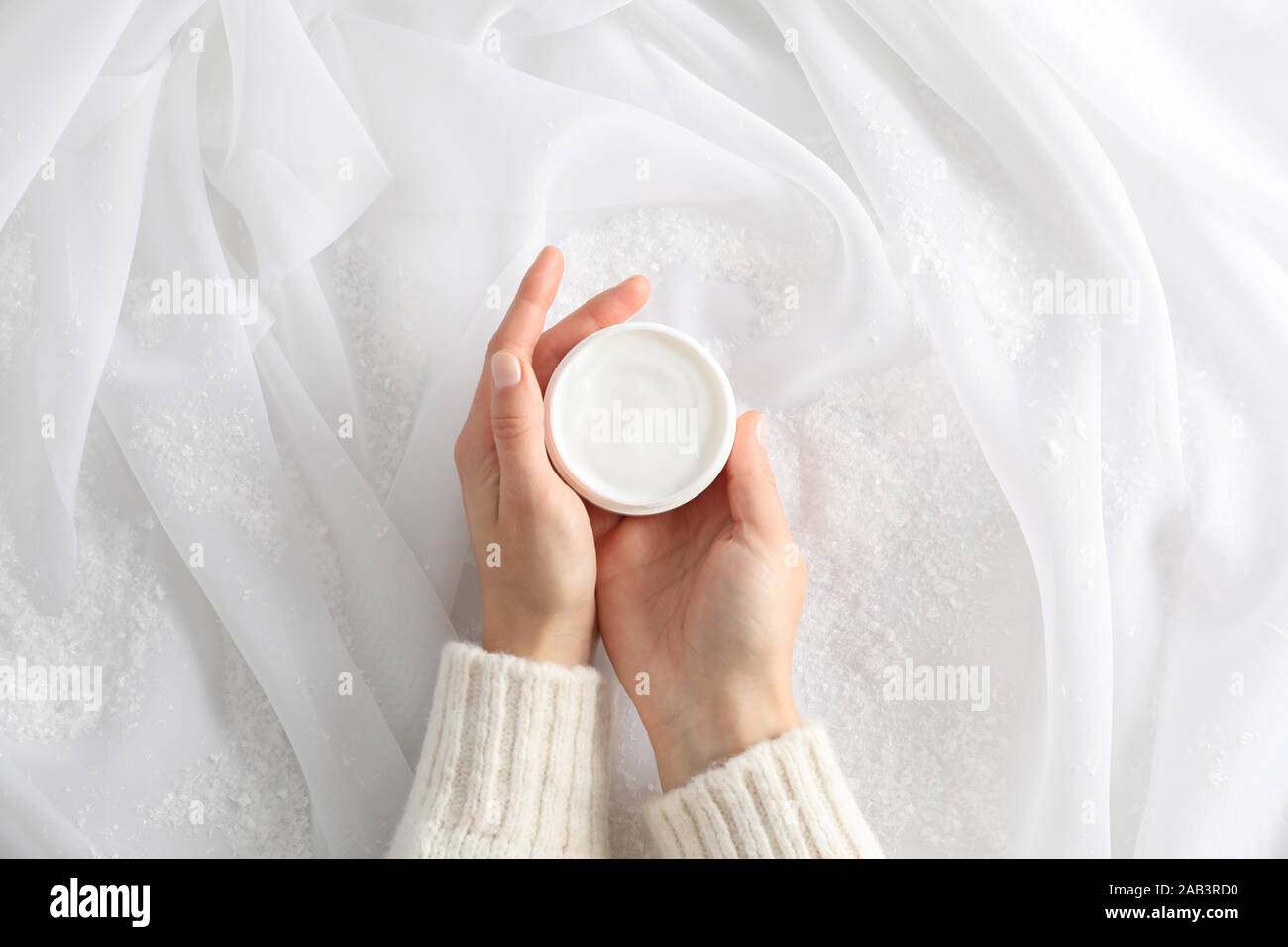 Frau mit Krug winter Creme für die Haut, dekorative Schnee auf weißem Stoff Hintergrund, Ansicht von oben. Platz für Text Stockfoto