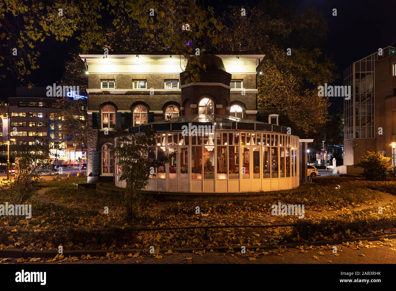 Eindhoven, Niederlande, 7. November 2019. Blick auf ein Restaurant Het zusje bei Nacht mit verschiedenen goldenen Farblicht und ein Wintergarten, surrou Stockfoto