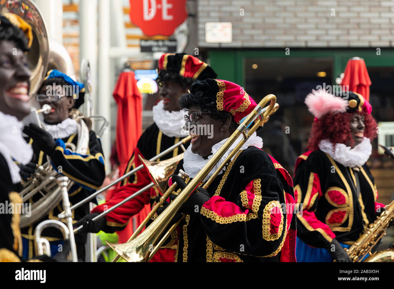 Eindhoven, Niederlande, 23. November 2019. Happy Pieten tragen ihren bunten Kostümen in einer Blaskapelle spielen Sinterklaas Musik ans lächelnd. Stockfoto