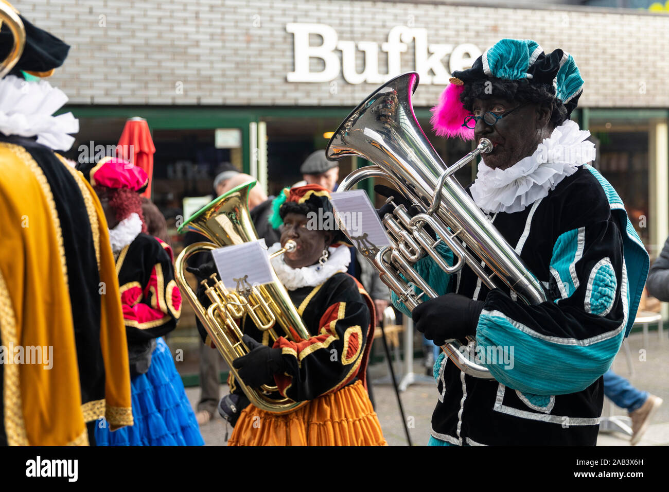 Eindhoven, Niederlande, 23. November 2019. Ein piet tragen ein buntes Kostüm in einer Blaskapelle spielen Sinterklaas Musik auf einer Trompete. Niederländische tra Stockfoto