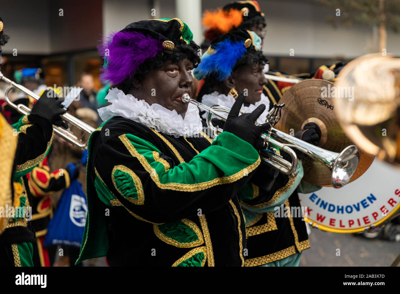 Eindhoven, Niederlande, 23. November 2019. Ein piet tragen ein buntes Kostüm in einer Blaskapelle spielen Sinterklaas Musik auf einer Trompete. Niederländische tra Stockfoto
