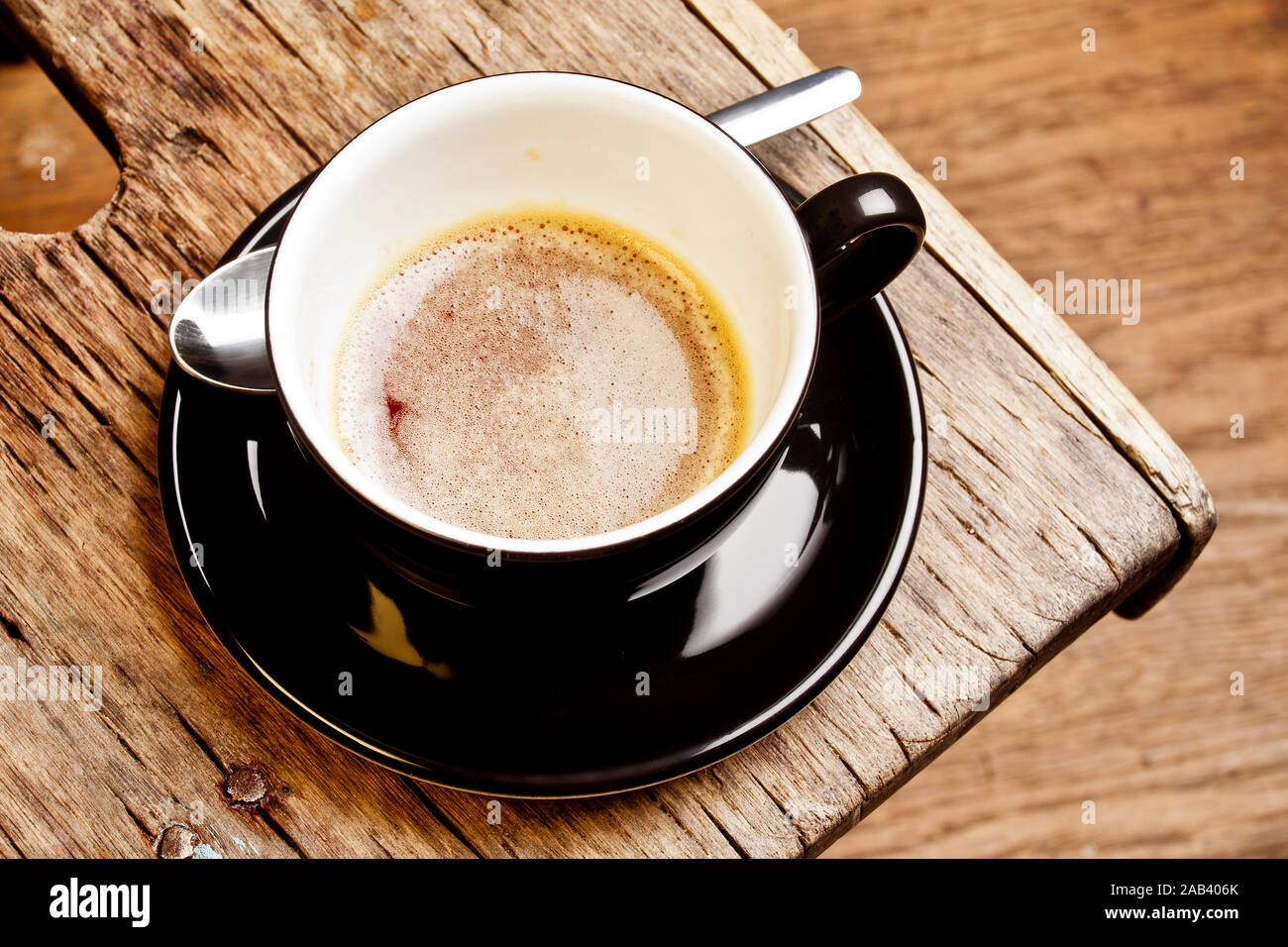 Eine halbvolle Tasse mit Espresso in einem alten Holzhocker | eine Hälfte - volle Tasse Espresso auf einem alten hölzernen Hocker | Stockfoto