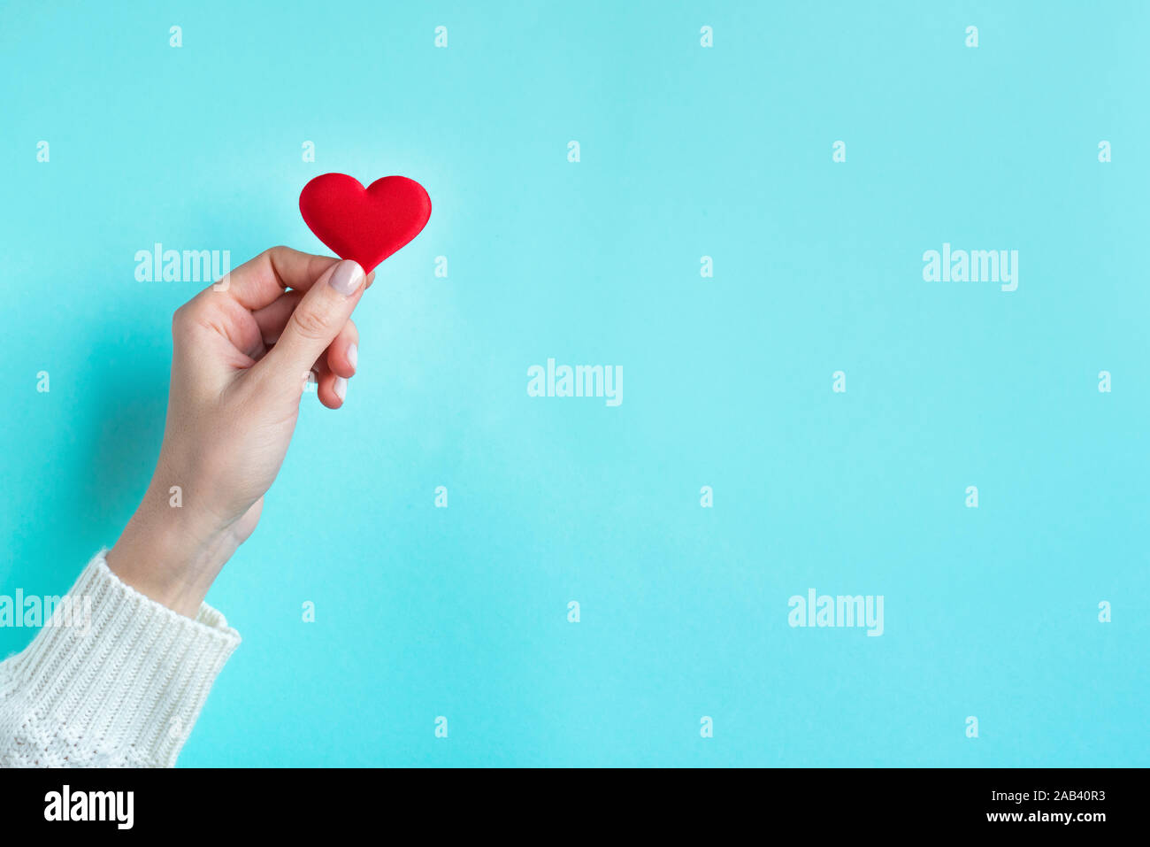 Hand halten roten Herzen, blauer Hintergrund mit kopieren. Valentinstag, Liebe, Nächstenliebe und Dankbarkeit trendige Konzept. Stockfoto
