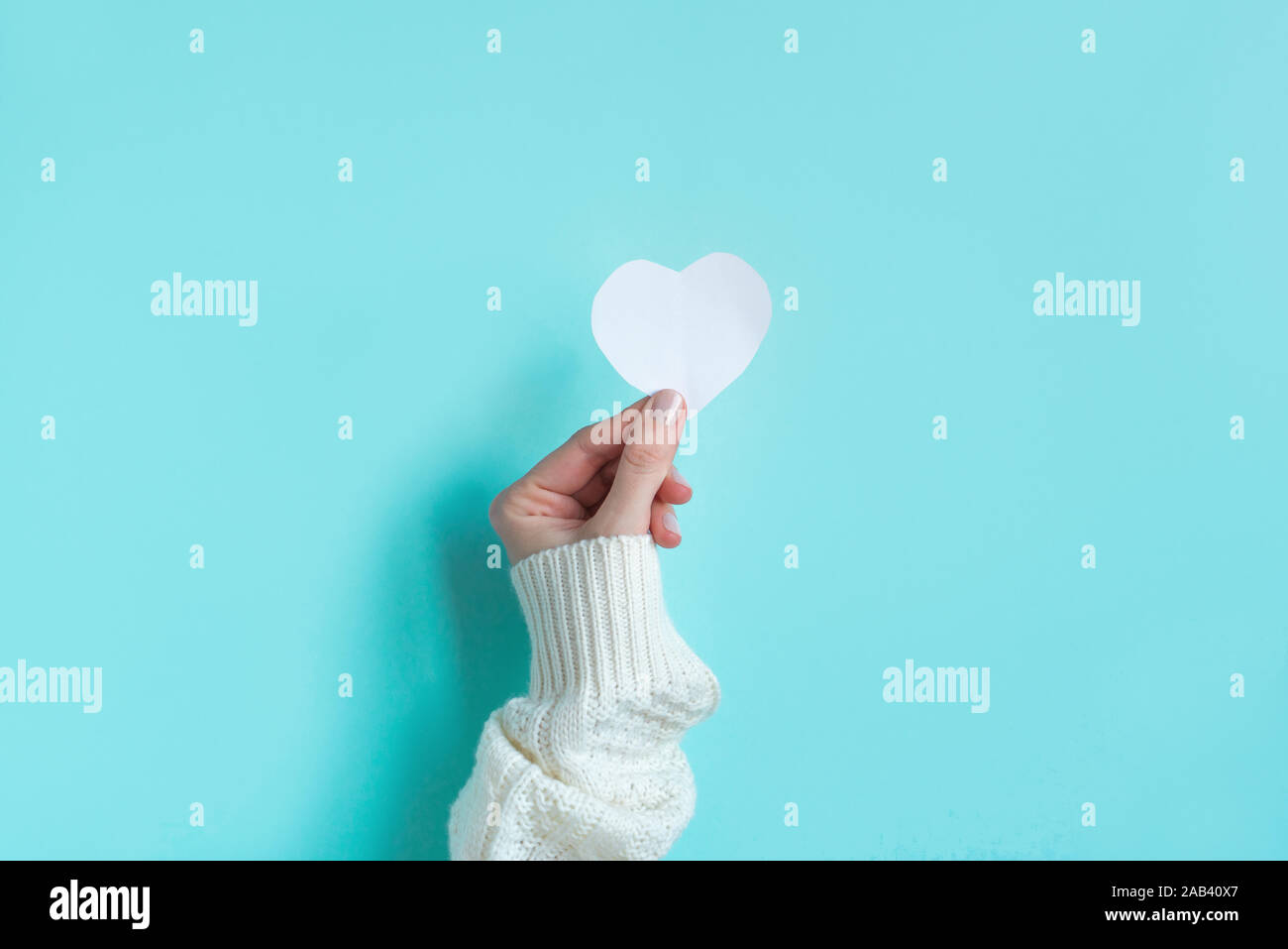 Hand, die weiße Leere Herzen, blauer Hintergrund mit kopieren. Valentinstag, Liebe, Nächstenliebe und Dankbarkeit trendige Konzept. Stockfoto