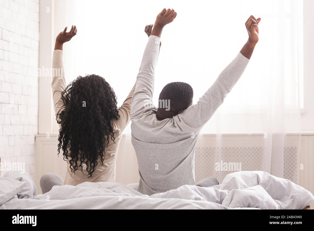 Entspannt afro Paar sitzt auf dem Bett, Stretching nach dem Ruhezustand Stockfoto