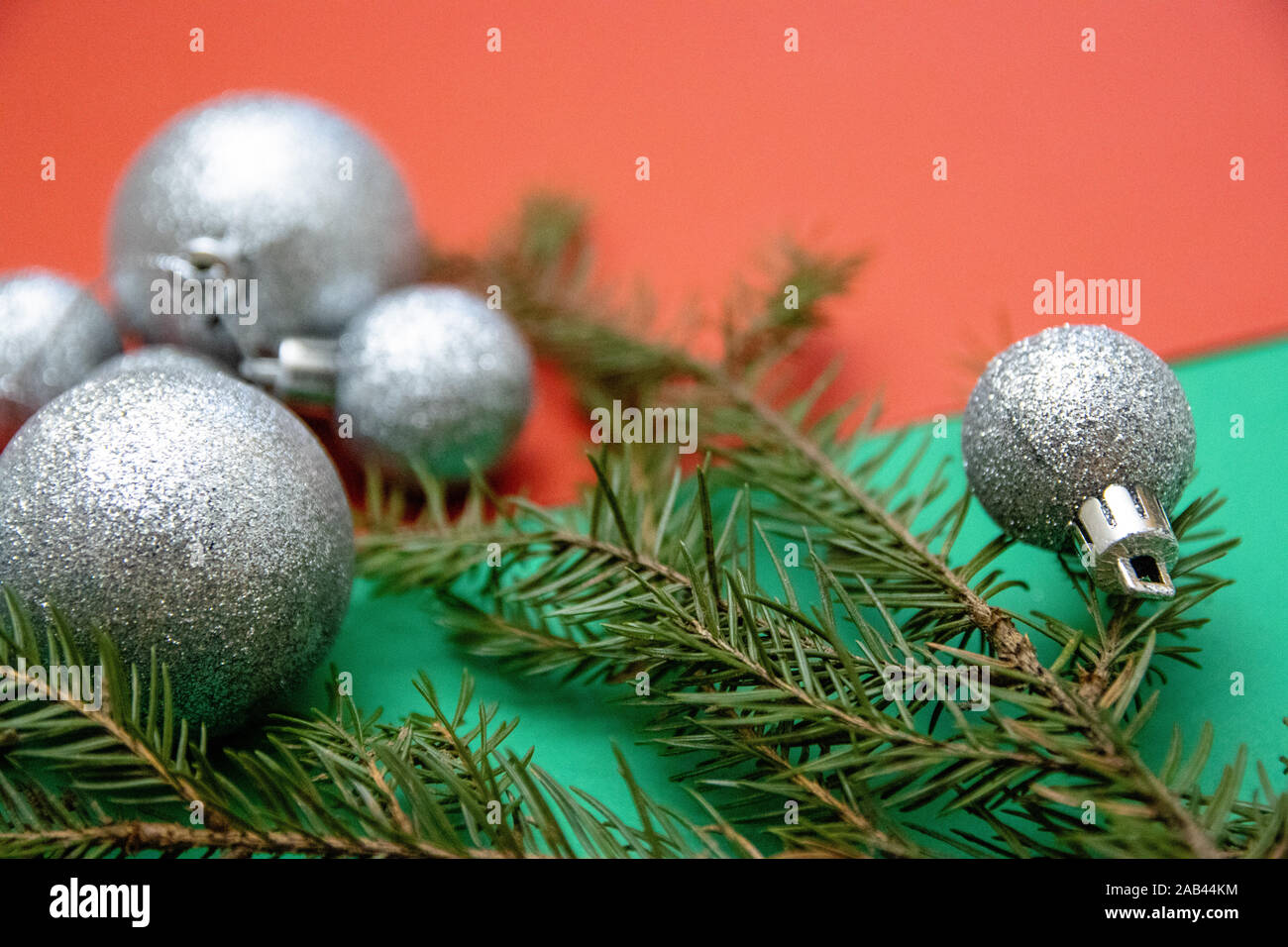 Weihnachten Fotos mit silber Baum Kugeln und Zweige von Nadelgehölzen auf einer rot-grünen Hintergrund Stockfoto