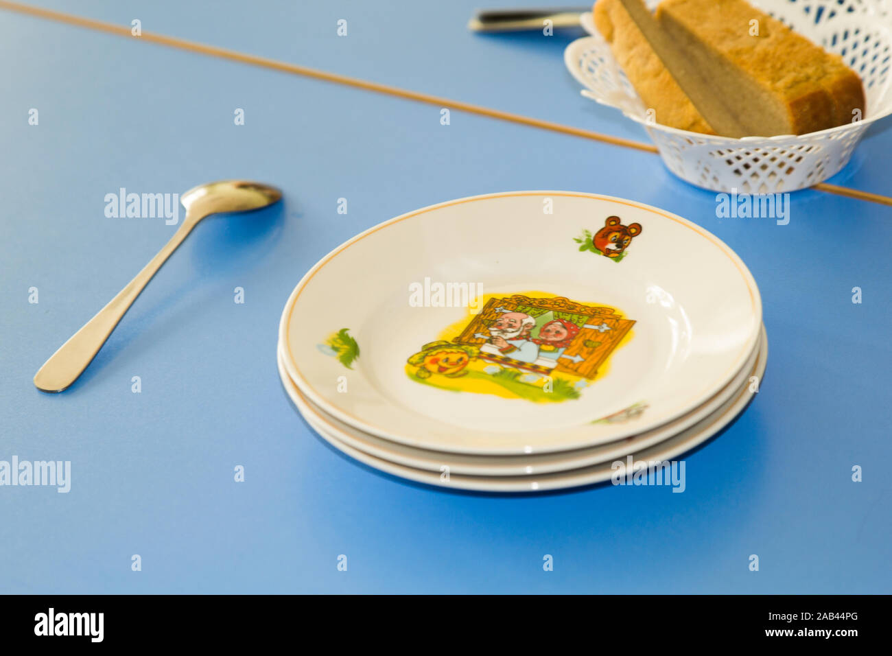 Serviert Esstisch für Kinder mit Brot, Teller mit Illustrationen. Farbenfroher Kindertisch. Kindergarten zur Mittagszeit. Stockfoto