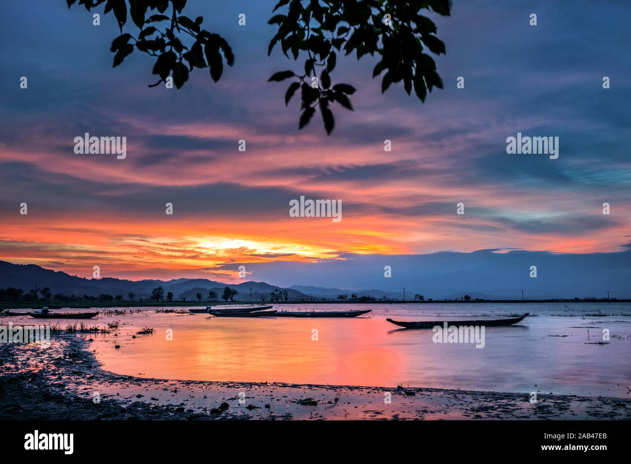 Berglandschaft, See- und Bergkette, großer See und Boot. Schöner Sonnenuntergang spiegelt sich im Lak See, Buon Me Thuot, Vietnam wider Stockfoto