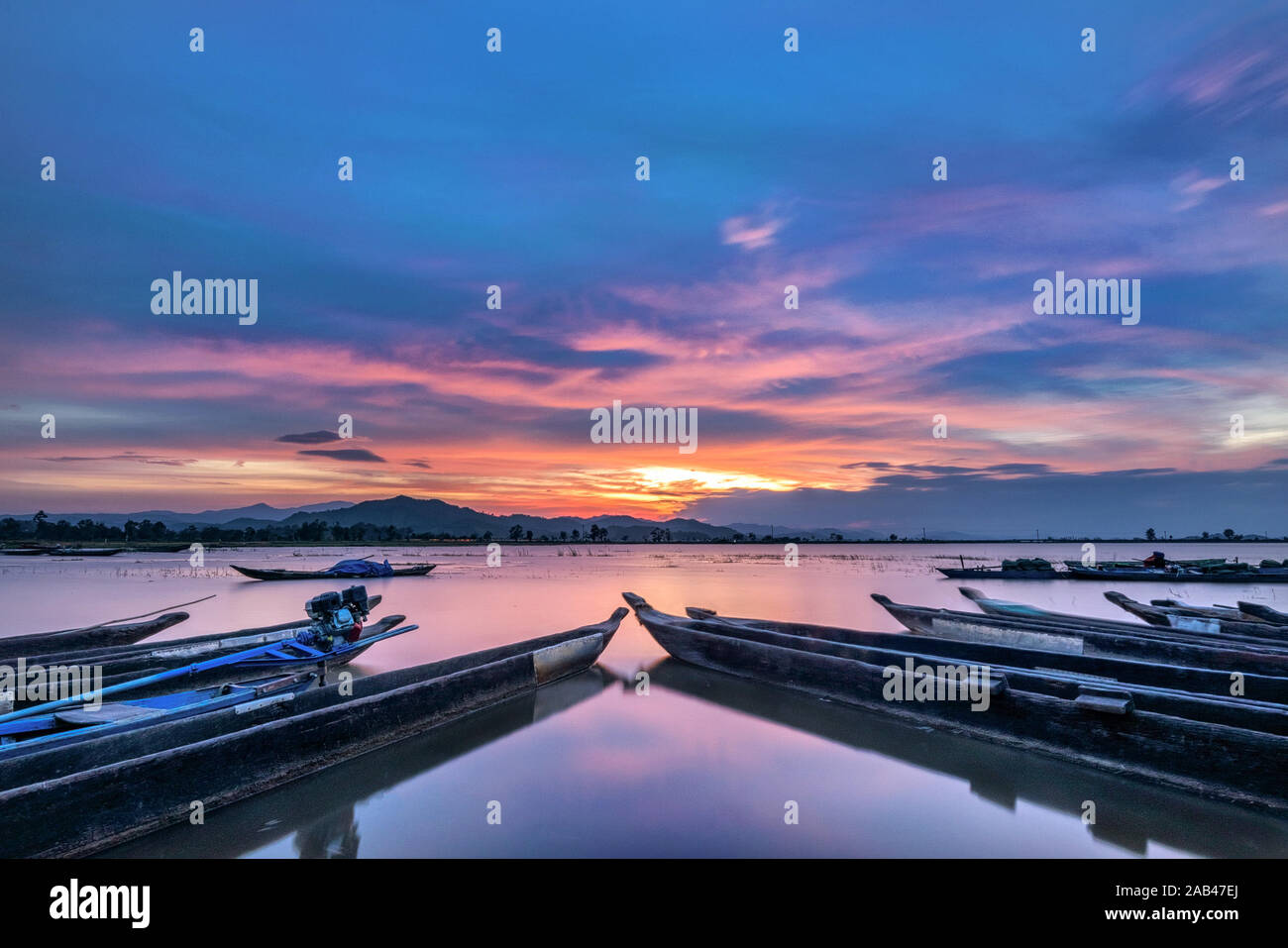 Berglandschaft, See- und Bergkette, großer See und Boot. Schöner Sonnenuntergang spiegelt sich im Lak See, Buon Me Thuot, Vietnam wider Stockfoto
