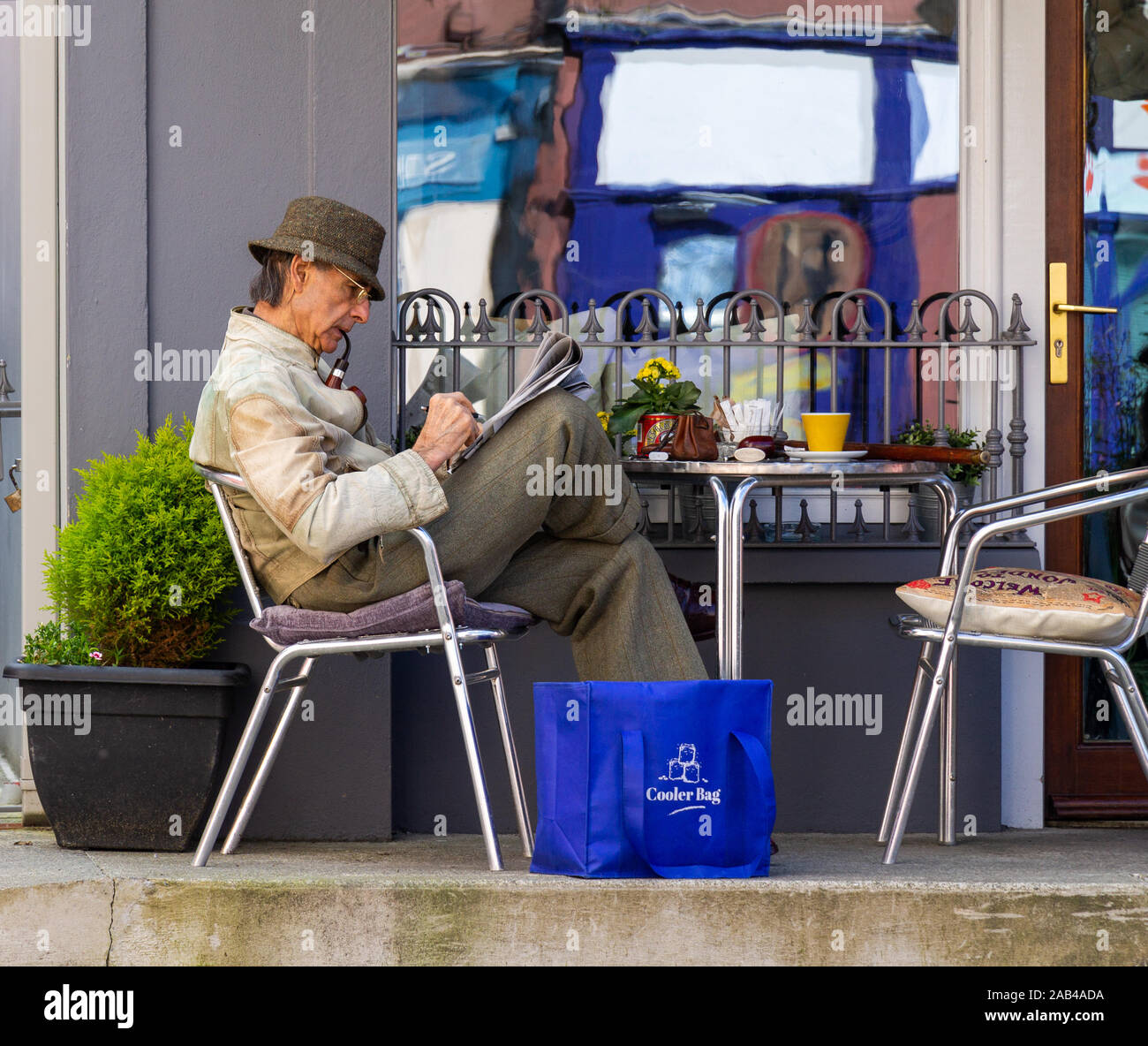 Pfeife rauchenden älteren Mann sassen draussen ein Cafe, das Kreuzworträtsel in der Zeitung Stockfoto