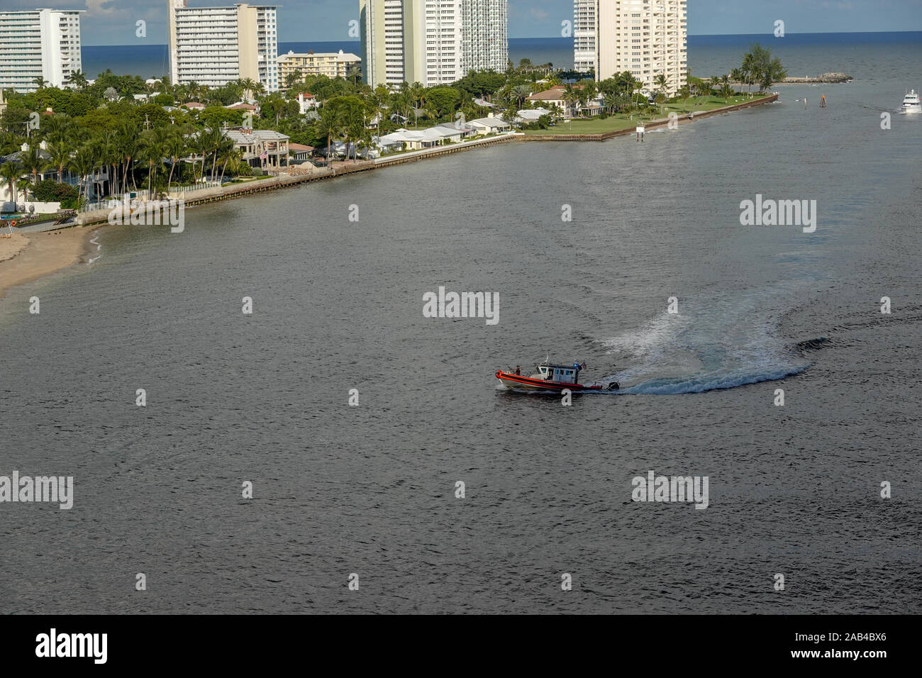 Ft. Lauderdale, FL/USA - 10/30/19: EINE US Coast Guard boat Escorts ein Kreuzfahrtschiff in den oder aus dem Hafen aus dem Ozean. Stockfoto