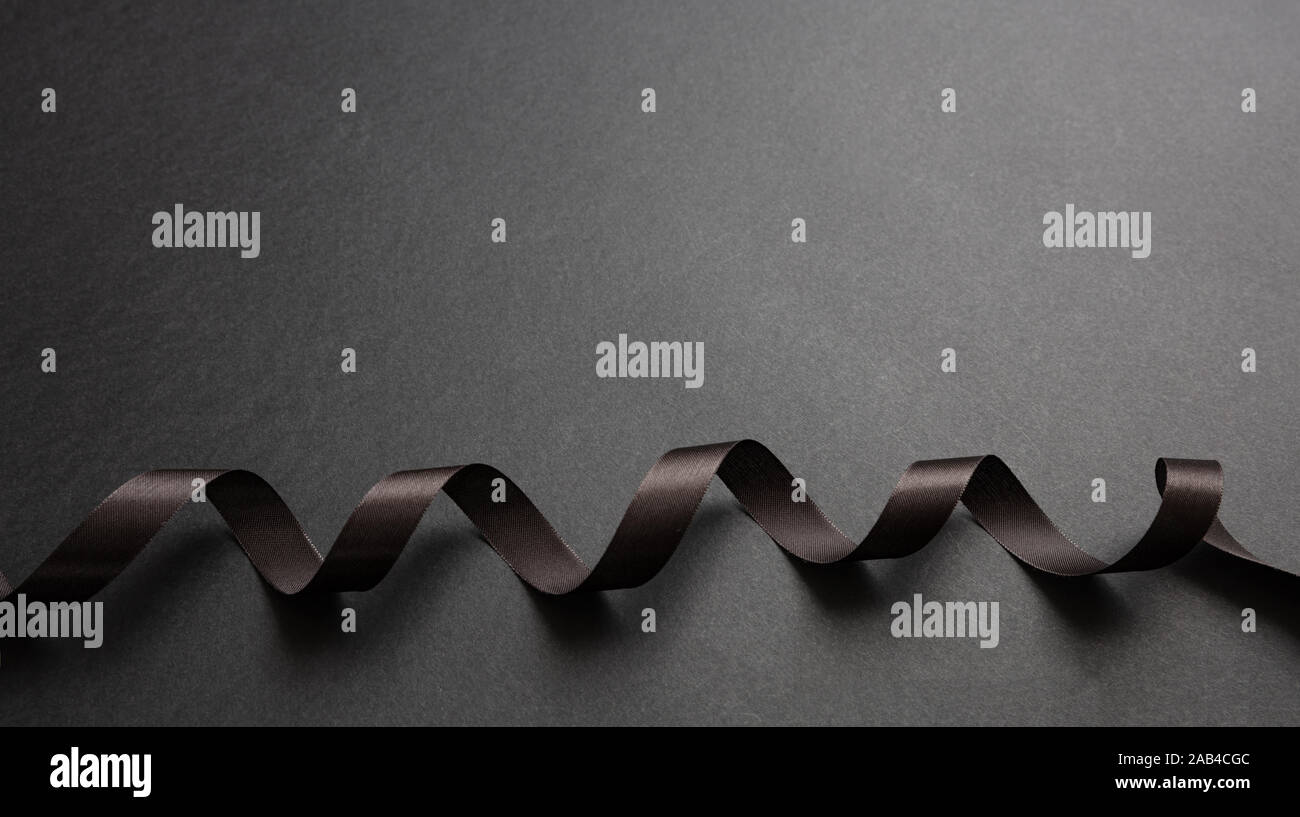 Schwarzes Band curly auf Schwarz Farbe Hintergrund, kopieren. Minimale schwarze Karte Vorlage Stockfoto