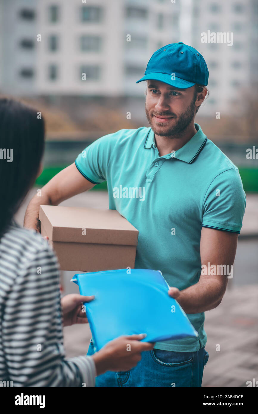Schöne bärtige Delivery Man Paket an seinem Client Stockfoto