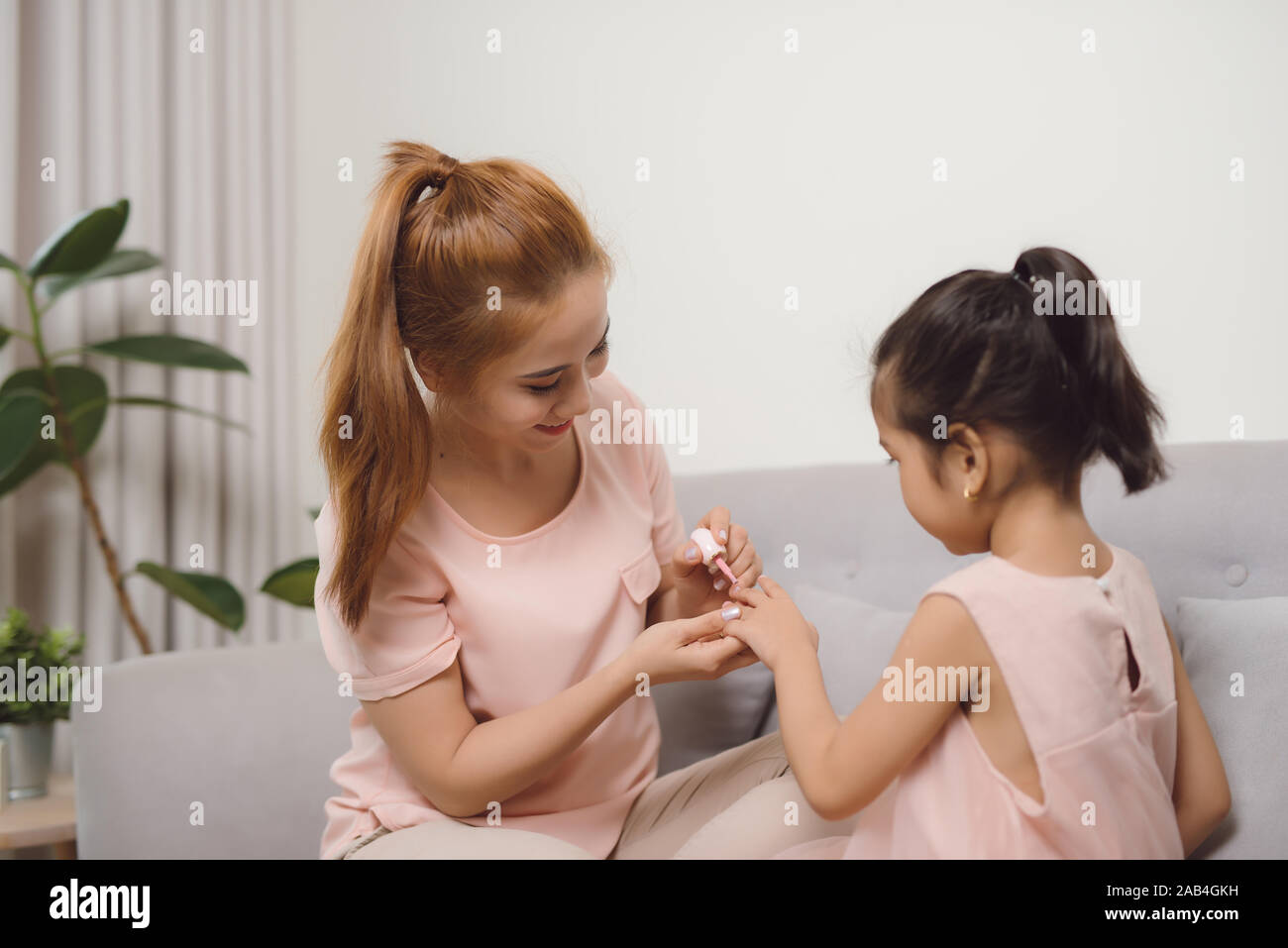 Schöne junge asiatische Mutter ist die Lackierung der Nagellack zu Ihrem süßen kleinen Tochter. Stockfoto