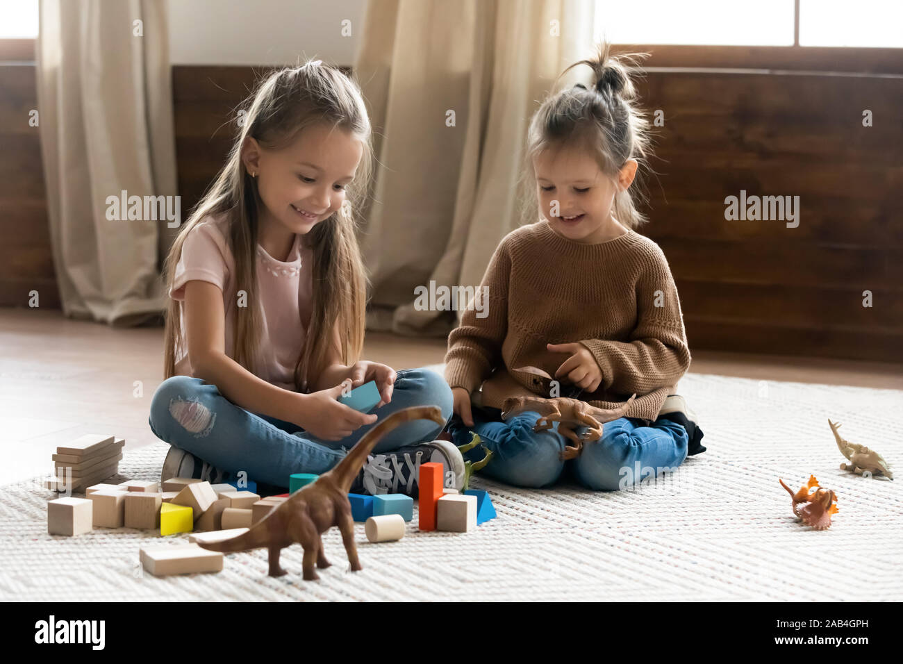 Glückliche Kinder Mädchen spielen Spielzeug sitzen auf dem Boden zu Hause Stockfoto