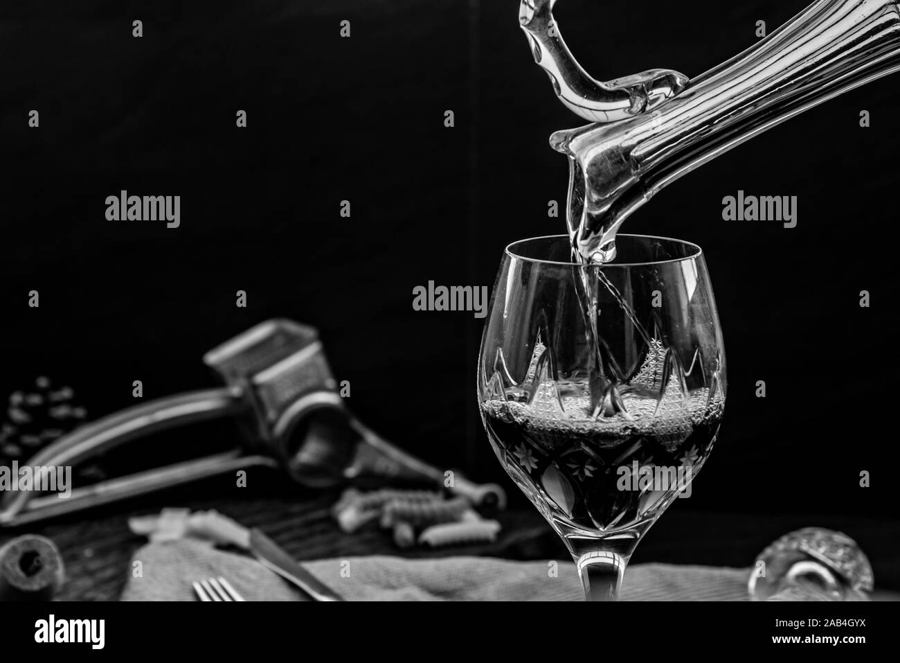 Schwarz-weiß Bild von Gießen Rotwein aus dem Krug in die WINEGLASS: traditionelle Weinbereitung und Weinproben Konzept, Freier Platz für Text. Stockfoto