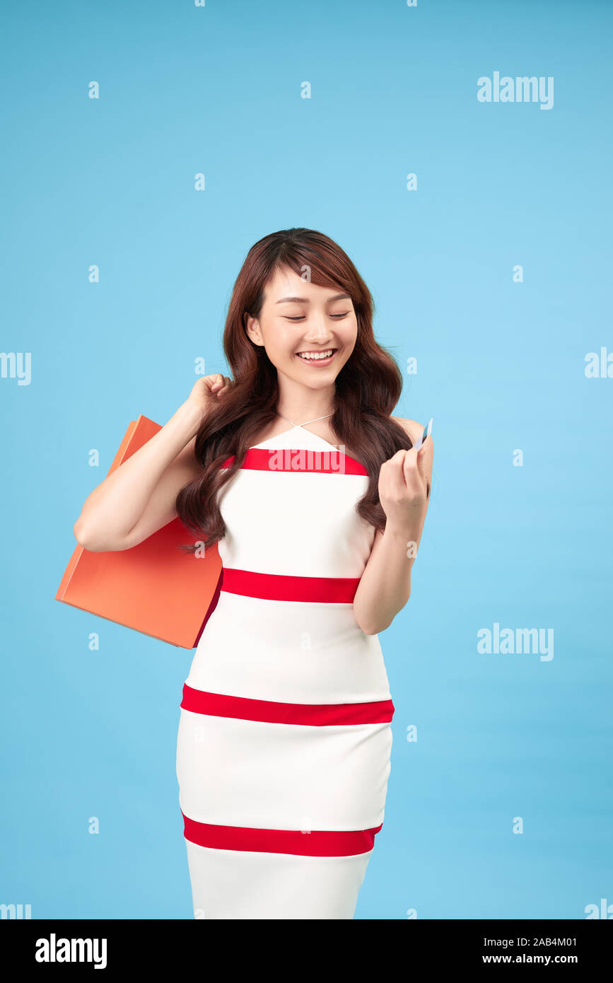 Hübsches Lächeln asiatische Frau mit Einkaufstüten, die Kreditkarte in der Hand studio Shot auf blauem Hintergrund isoliert Stockfoto