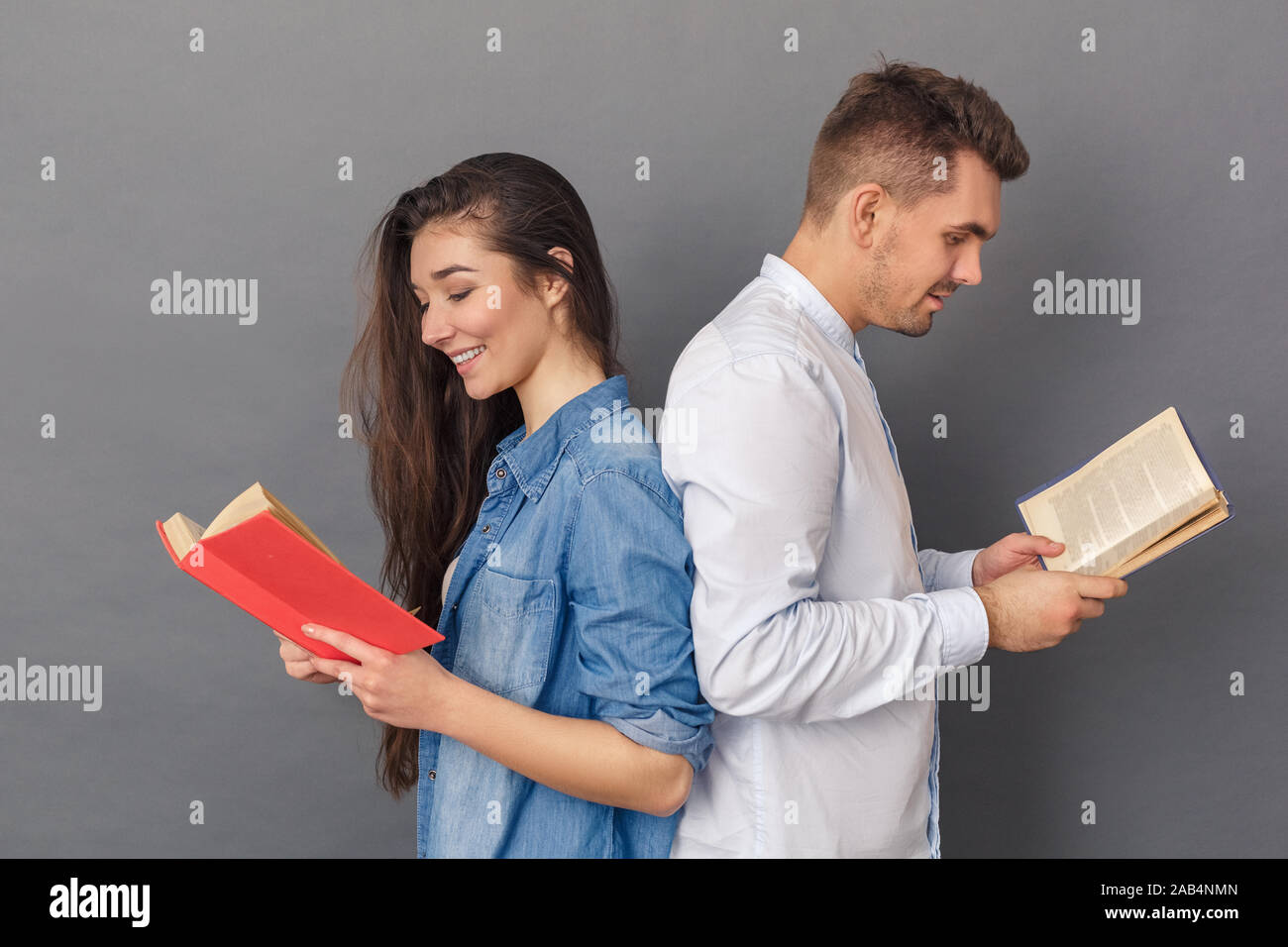 Beziehung Konzept. Junges Paar Studio zurück auf grau Bücher lesen isoliert zurück Frohe Stockfoto