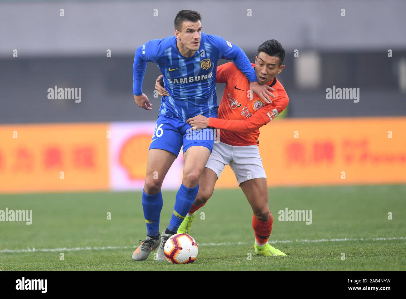 Kroatischen Fußball-Spieler Ivan Santini der Jiangsu Suning F.C., Links, schützt den Ball in der 28. Runde der Chinese Football Association Super League (CSL) gegen Peking Renhe in Peking, China, 23. November 2019. Peking Renhe wurde von Jiangsu Suning mit 2-3 besiegt auf der 28. Runde der Chinese Football Association Super League (CSL) und zwei Runden früher abgebaut wurde. Stockfoto