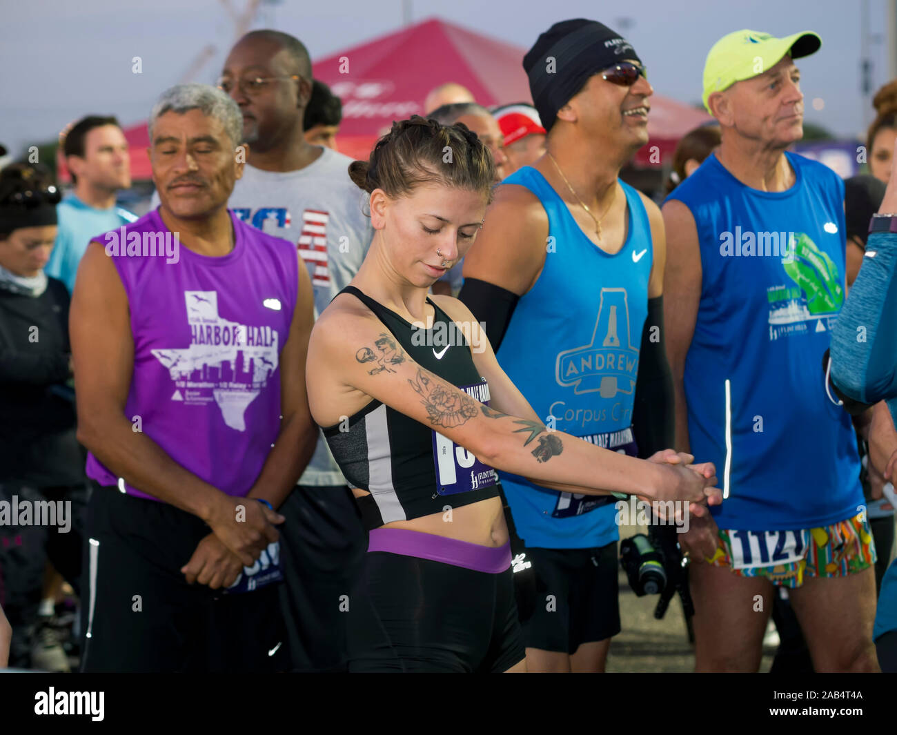 Kaukasische Frau tätowiert und andere Wettbewerber erwarten am frühen Morgen Start der Corpus Christi, Texas, USA 15. jährlichen Hafen Halbmarathon. Stockfoto