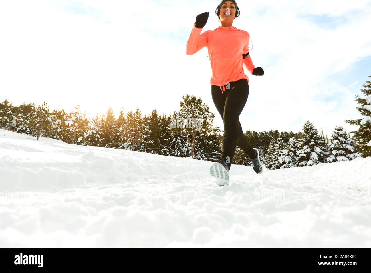 Lächelnd gesunde Frau Joggen im verschneiten Wald Stockfoto