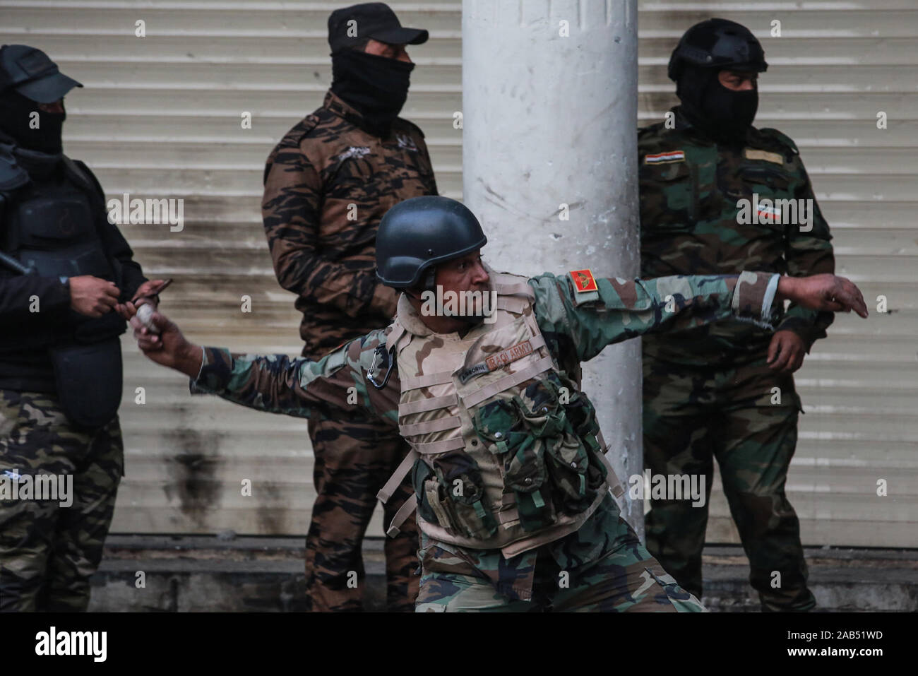 Bagdad, Irak. 25 Nov, 2019. Ein Mitglied der irakischen Sicherheitskräfte schleudert einen Stein auf regierungsfeindlichen Demonstranten während der gewalttätigen Auseinandersetzungen auf Al Rasheed Straße. Credit: Ameer Al Mohammedaw/dpa/Alamy leben Nachrichten Stockfoto