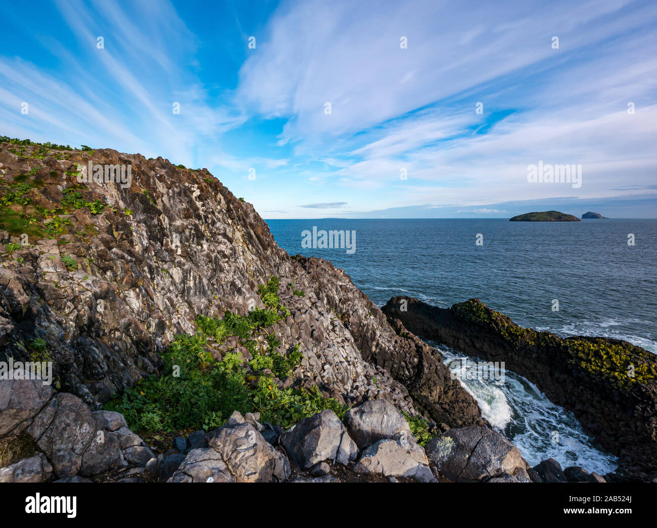 Rocky Cliff View aus Lamm Insel mit geschnittenen Baum Malve und Meer getragen Rocky Einlass am sonnigen Tag, Erhabene, Schottland, Großbritannien Stockfoto