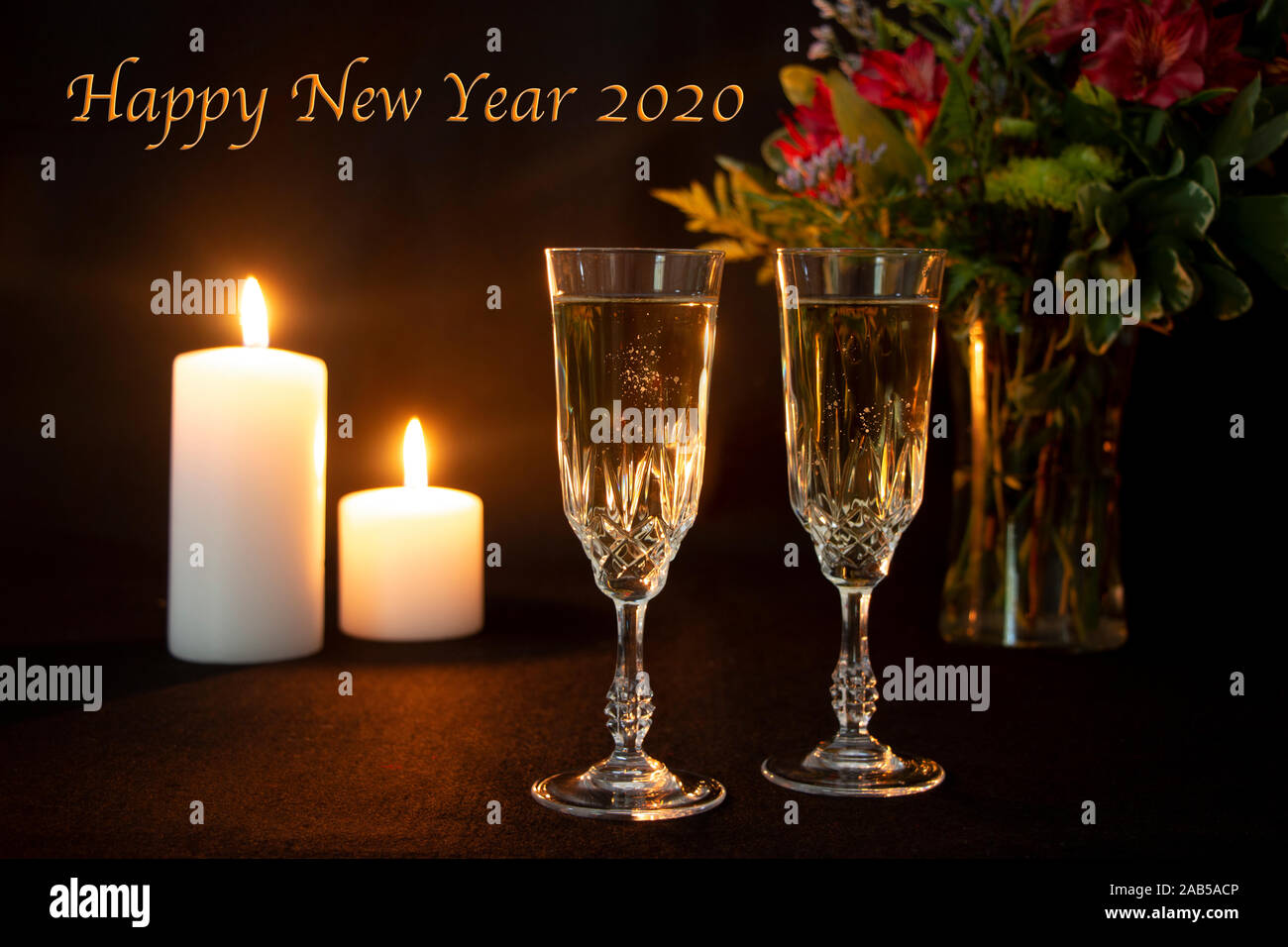 Frohes Neues Jahr 2020 Text mit Kerzen und zwei Champagnergläser Stockfoto